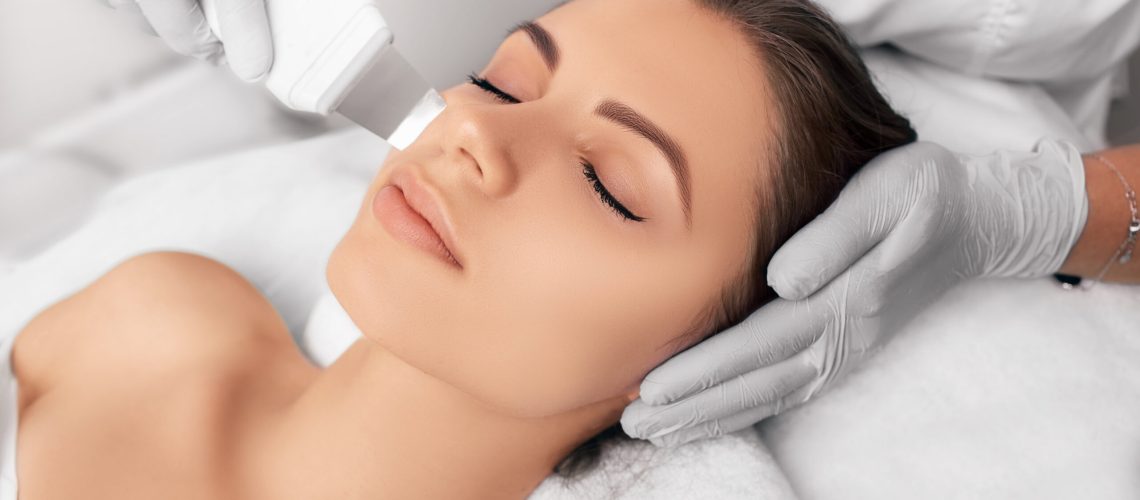 Beautiful woman receiving ultrasound cavitation facial peeling. Cosmetology and facial skin care